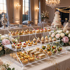 Espositore trasparente a tre livelli con pasticceria mignon e stuzzichini su un tavolo da buffet.